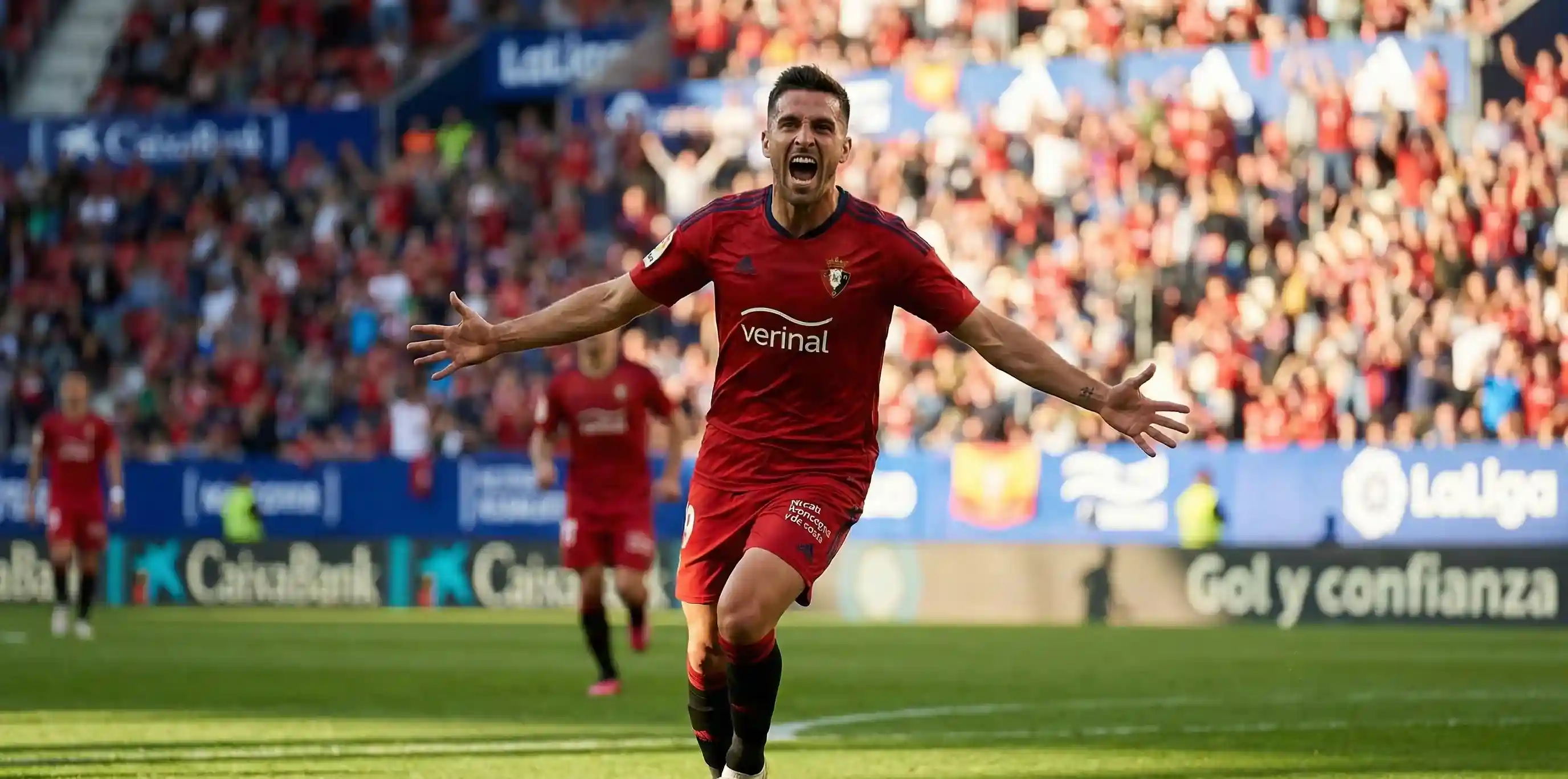 Delantero de fútbol profesional celebrando un gol con los brazos abiertos