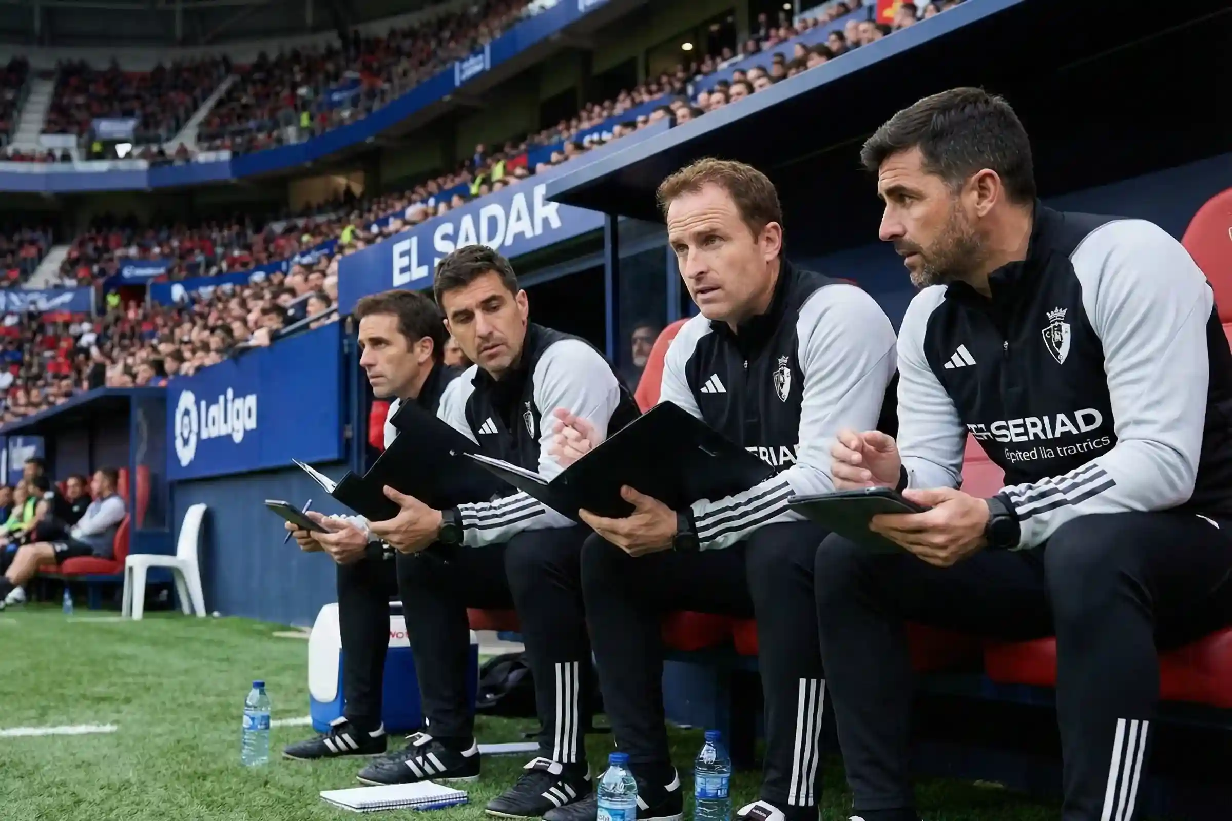 Entrenador y cuerpo t&eacute;cnico analizando el partido desde el banquillo