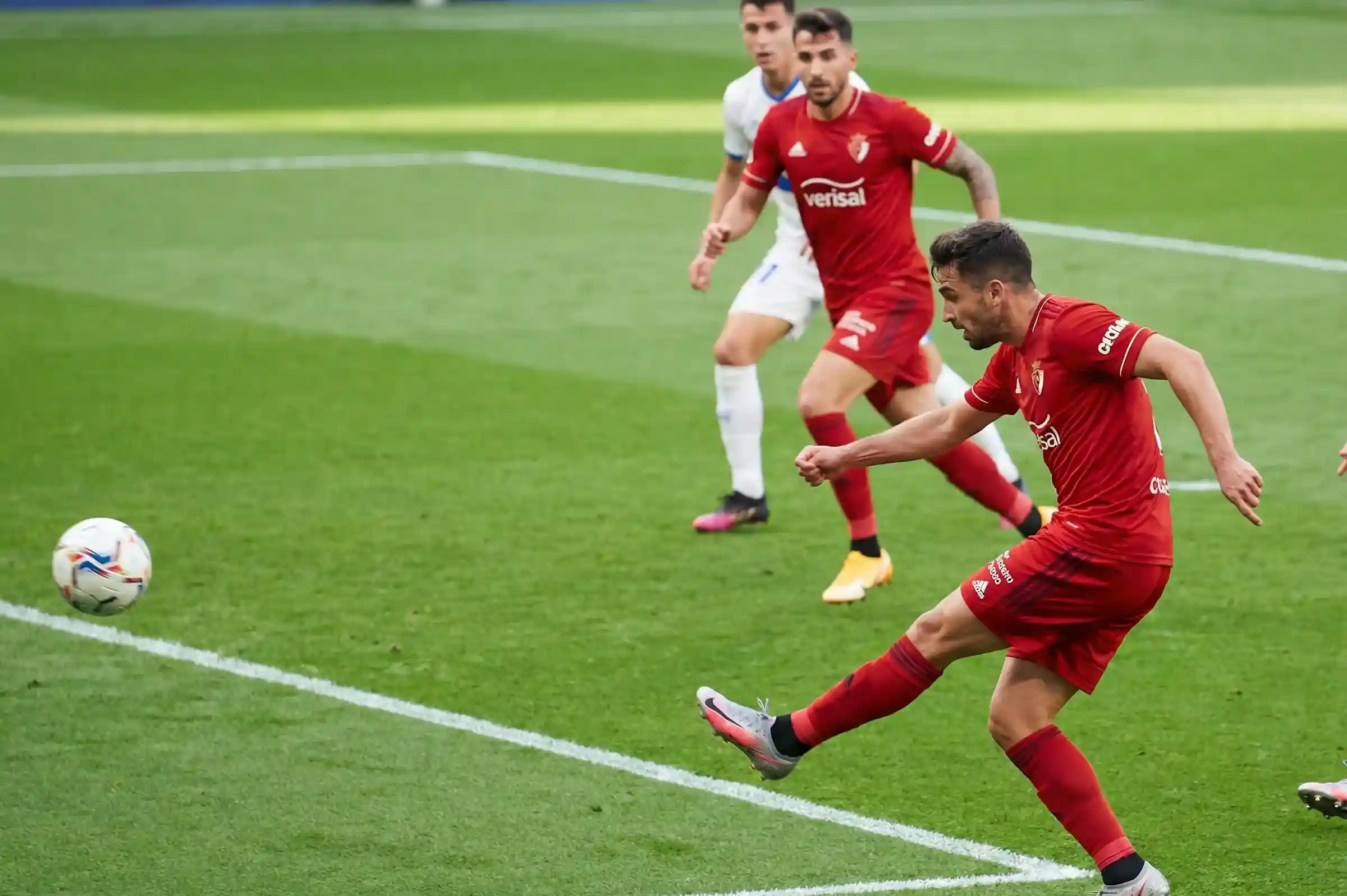 Jugador de f&uacute;tbol realizando un centro al &aacute;rea desde la banda